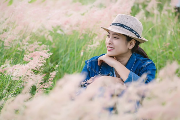 Feliz joven mujer asiática sentada en el campo de hierba