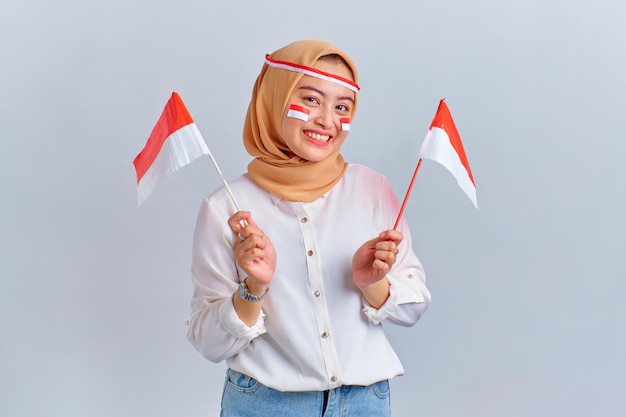 Feliz joven mujer asiática sosteniendo la bandera indonesia aislada sobre fondo blanco Concepto del día de la independencia de Indonesia