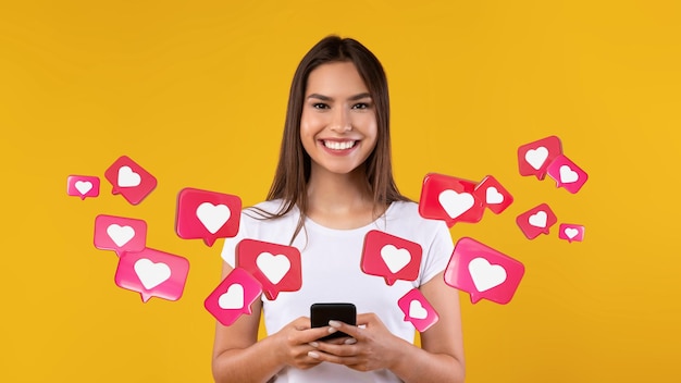 Feliz joven mujer caucásica tiene chat romántico con corazones en el teléfono disfruta de mensajes en las redes sociales