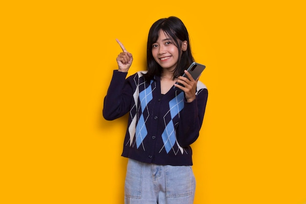 feliz joven mujer hermosa asiática usando teléfono móvil aislado sobre fondo amarillo