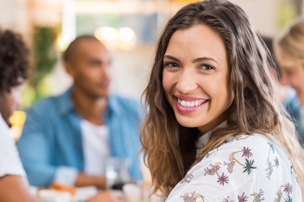 Feliz joven mujer multiétnica cara desayunando con sus amigos en la pared