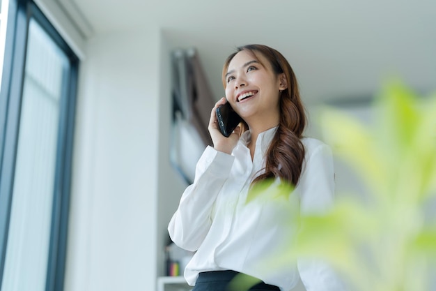 Feliz joven mujer de negocios asiática con traje con teléfono móvil