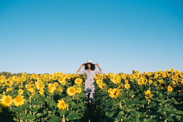 Feliz joven mujer negra caminando en un campo de girasol