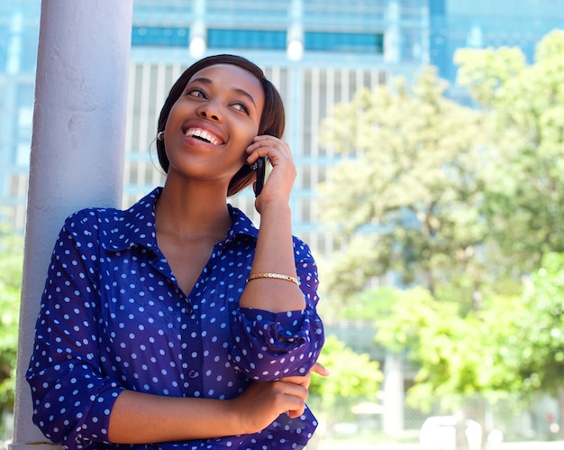 Feliz joven mujer negra llamando por teléfono móvil