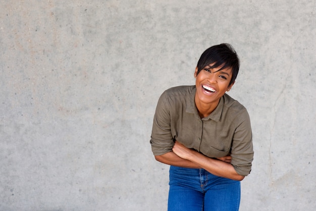 Feliz joven mujer negra riendo contra el fondo gris