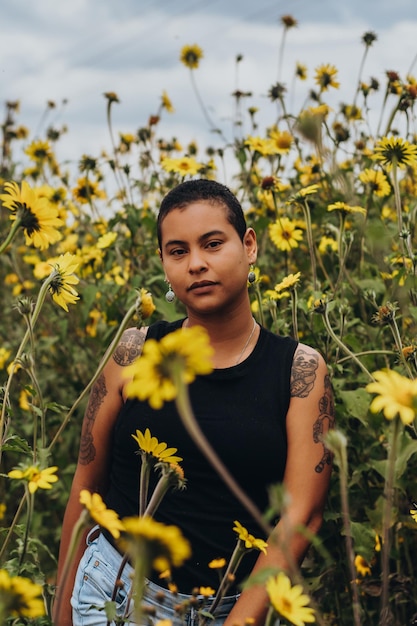 Feliz joven mujer de pelo corto con rasgos afrolatinos Retrato de una mujer rodeada de flores vistiendo ropa de verano disfrutando de la naturaleza