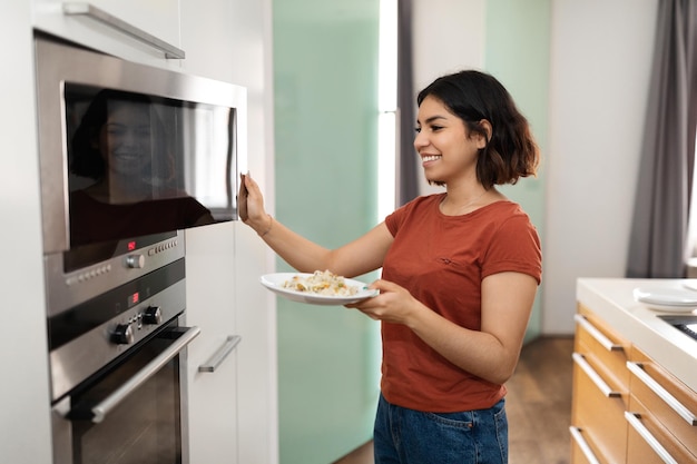 Feliz Joven Mujer Árabe Calentando La Comida En El Microondas En La Cocina