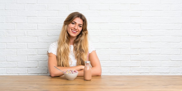 Feliz joven mujer rubia con tazón de cereales