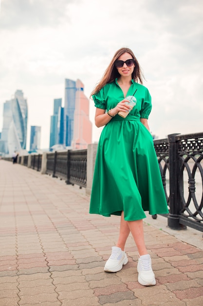 Feliz joven mujer urbana tomando café en ciudad europea