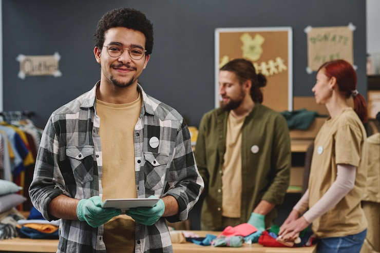 Foto feliz joven multiétnico voluntario masculino sosteniendo tableta