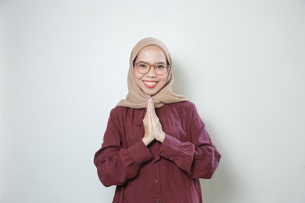 Feliz joven musulmana asiática con anteojos saludando con ambas manos aisladas