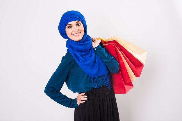 Feliz joven musulmana con bolsa de compras sobre fondo blanco.