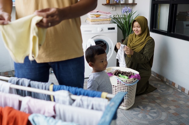 Feliz joven musulmana y su marido lavando la ropa juntos en casa
