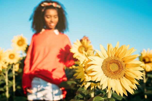 Feliz joven negra caminando en un campo de girasol