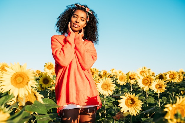 Feliz joven negra caminando en un campo de girasol