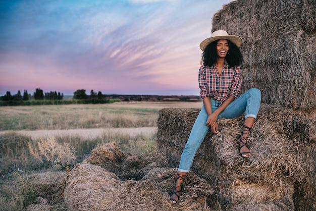 Feliz joven negra sentada en un montón de heno