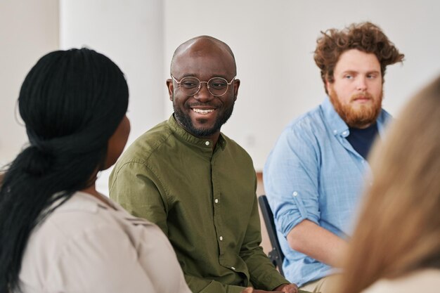 Feliz joven negro mirando a uno de los pacientes durante la sesión psicológica