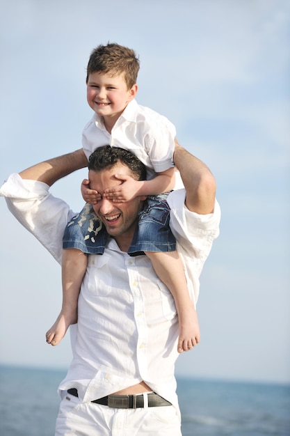 feliz joven padre e hijo se divierten y disfrutan del tiempo en la playa al atardecer y representan un concepto familiar y de apoyo saludable