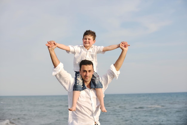 feliz joven padre e hijo se divierten y disfrutan del tiempo en la playa al atardecer y representan un concepto familiar y de apoyo saludable