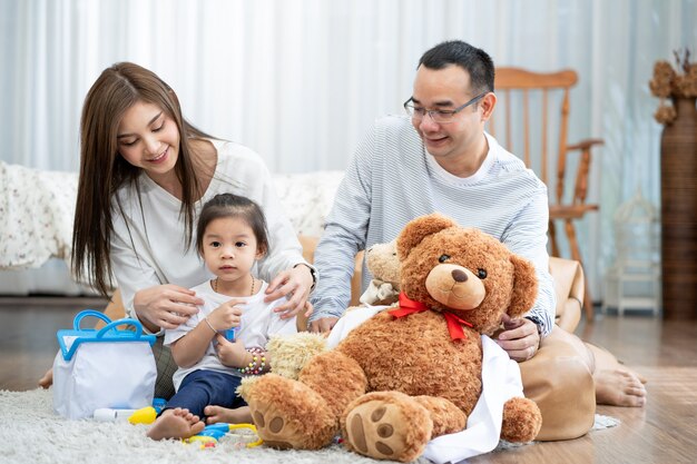 Feliz joven padre y madre y una pequeña hija jugando con juguetes, sentados en el suelo en la sala de estar, la familia, la paternidad y el concepto de personas