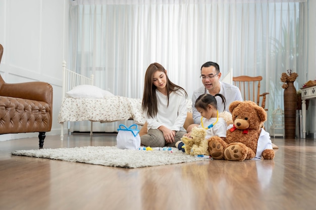 Feliz joven padre y madre y una pequeña hija jugando con juguetes, sentados en el suelo en la sala de estar, la familia, la paternidad y el concepto de personas