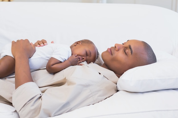 Feliz joven padre siesta con hijo en el sofá