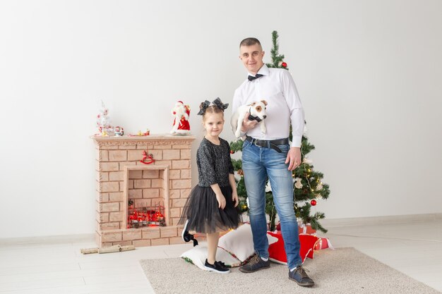 Feliz joven padre y su hija en casa con árbol de Navidad.