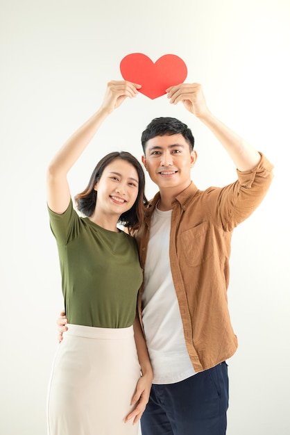 Feliz joven pareja asiática sosteniendo en forma de corazón sobre fondo blanco.