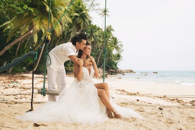 Feliz joven pareja casada celebrando su boda en la playa