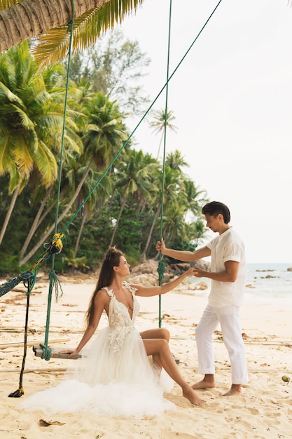 Feliz joven pareja casada celebrando su boda en la playa