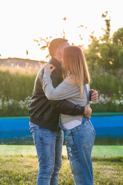 Feliz y joven pareja embarazada abrazándose en la naturaleza