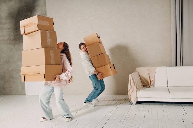 Feliz joven pareja familiar, hombre y mujer, mudándose con cajas de cartón apiladas a un nuevo apartamento en casa