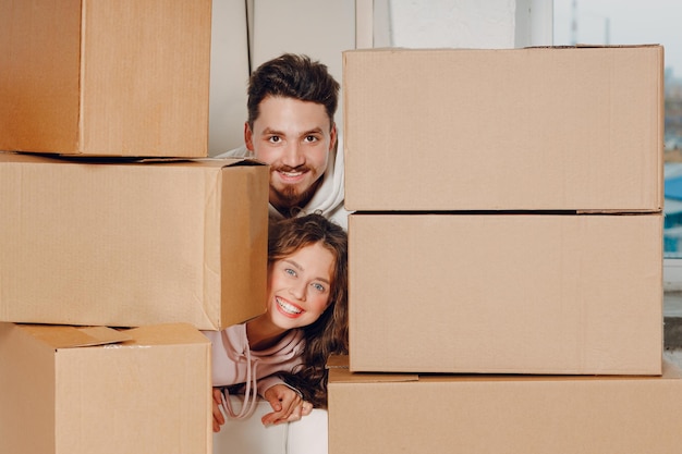 Feliz joven pareja familiar retrato de hombre y mujer relajándose después de mover cajas de cartón a un nuevo apartamento inmobiliario