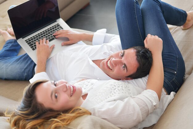 feliz joven pareja relajada trabajando y jugando en la computadora portátil en casa