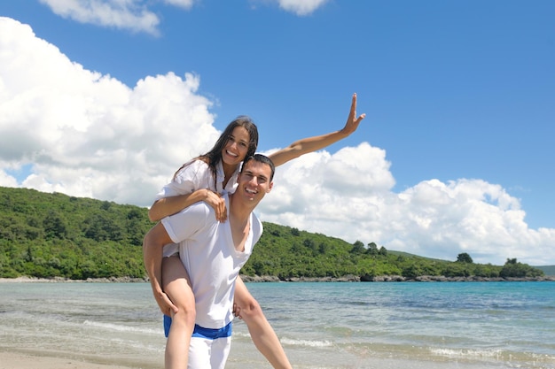 feliz joven pareja romántica enamorada diviértete corriendo y relajándote en la hermosa playa