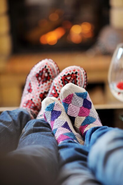 Foto feliz joven pareja romántica sentada en un sofá frente a la chimenea en la temporada de invierno en casa