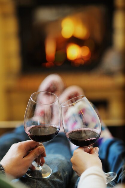 feliz joven pareja romántica sentada en un sofá frente a la chimenea en la temporada de invierno en casa