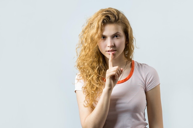 Feliz joven pelirroja caucásica con camisa de verano sostiene la cabeza La chica preocupada mira con cautela hacia un lado sintiéndose presionada y perpleja