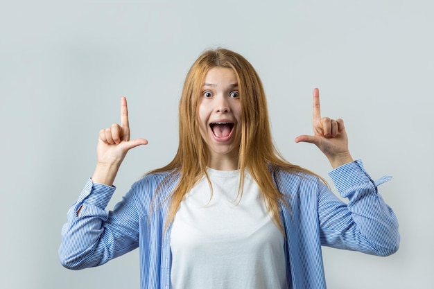 Feliz joven pelirroja caucásica mujer en camisa de verano señalando con el dedo mostrando espacio de copia para su texto