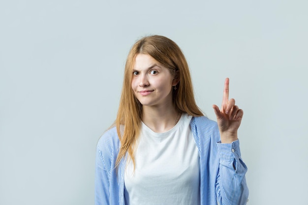 Feliz joven pelirroja caucásica mujer en camisa de verano señalando con el dedo mostrando espacio de copia para su texto