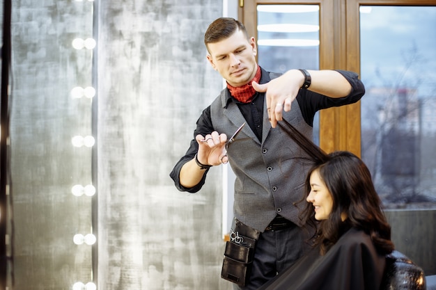 feliz joven y peluquería cortando puntas de cabello en el salón.