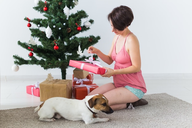 Feliz joven con perro encantador abriendo regalos de Navidad