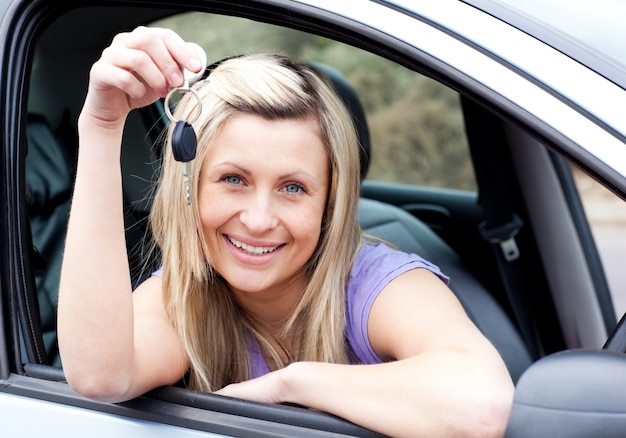 Feliz joven piloto sosteniendo una llave después de bying un coche nuevo