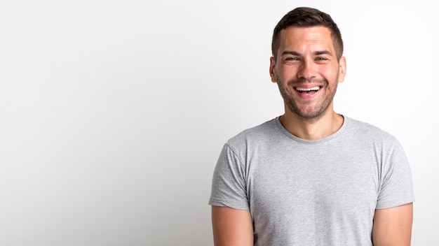 Feliz joven rastrojo riendo y de pie sobre fondo blanco