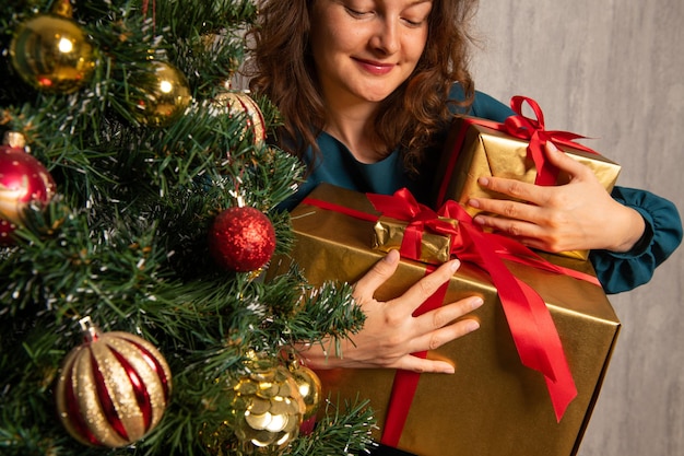 Feliz joven recibiendo regalos de año nuevo cerca del árbol de Navidad