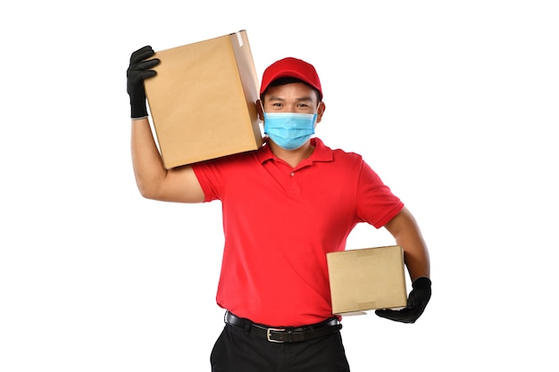 Feliz joven repartidor asiático en uniforme rojo, mascarilla médica, guantes protectores llevan caja de cartón