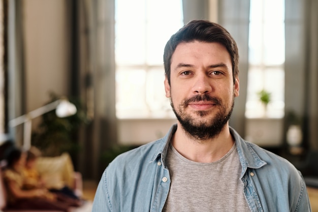 Feliz joven en ropa casual mirándote en la sala de estar