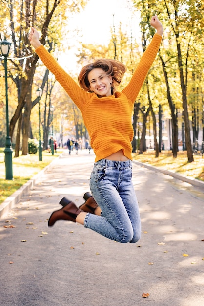 Feliz joven saltando en otoño en el parque