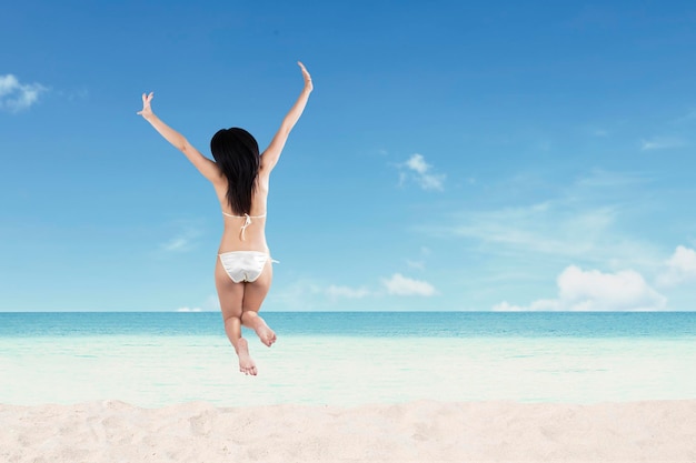 Feliz joven saltando en la playa