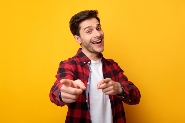 Feliz joven señalando con el dedo a la cámara en el estudio